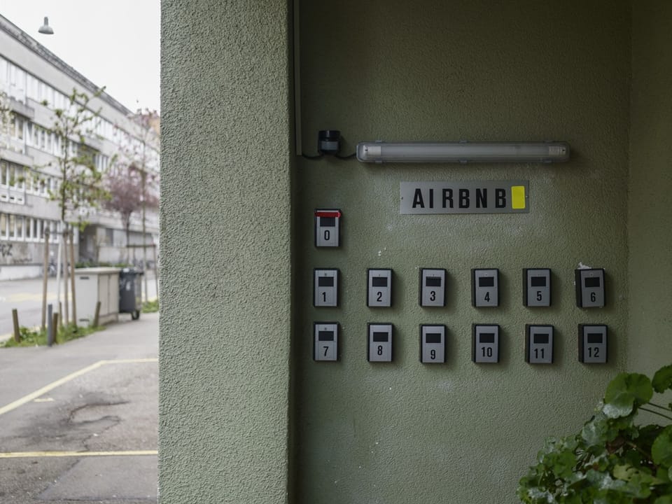 13 Schlüsselkästen an einer Hauswand. Darüber ein Schild, auf dem airbnb steht.