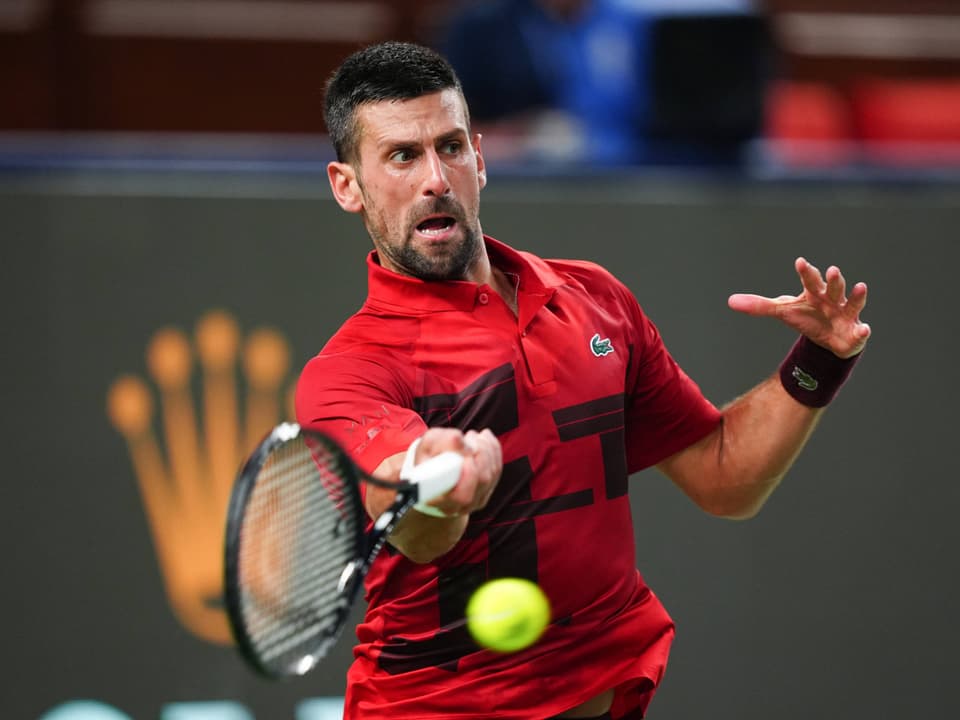 Tennisspieler im roten Hemd beim Schläger-Schwingen.