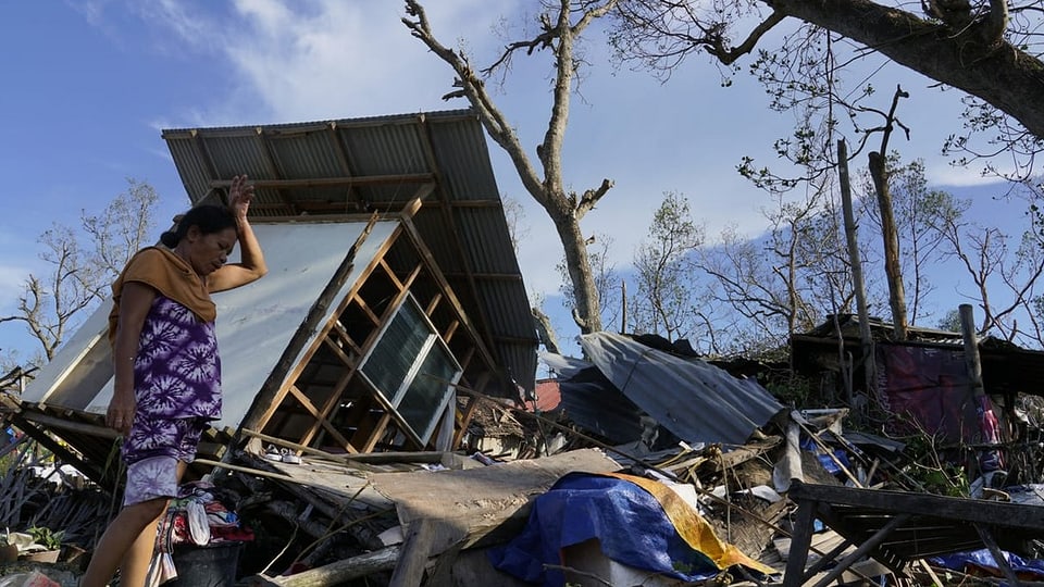 Eine Frau blickt in der Provinz Cebu auf ihr zerstörtes Zuhause.
