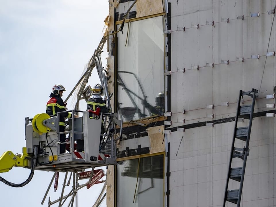 Feuerwehrleute retten an einem beschädigten Gebäude.