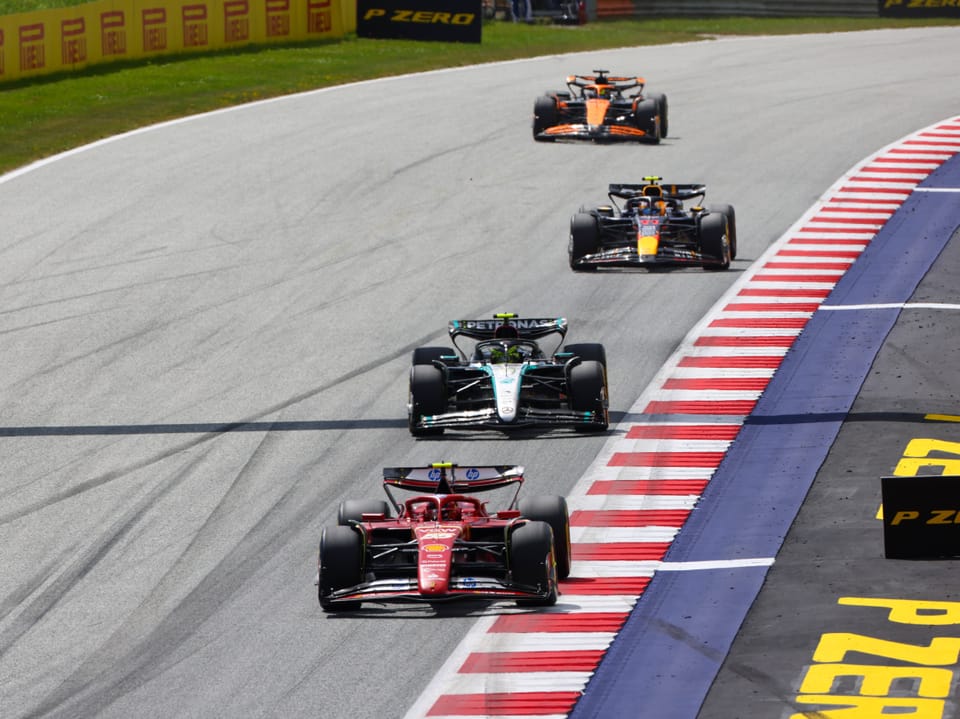 Vier Formel-1-Autos im Rennen auf einer Strecke.