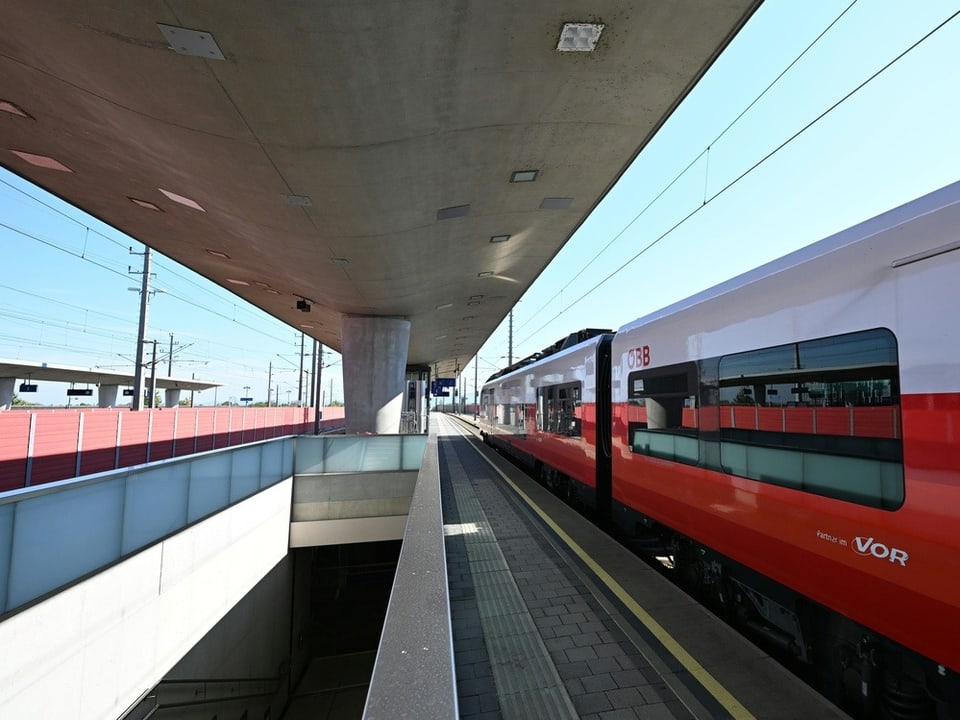 Moderner Bahnhof mit Zug am Bahnsteig.