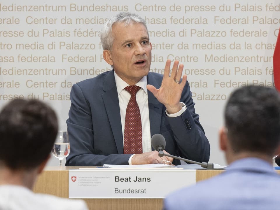 Mann in Anzug spricht bei Pressekonferenz.