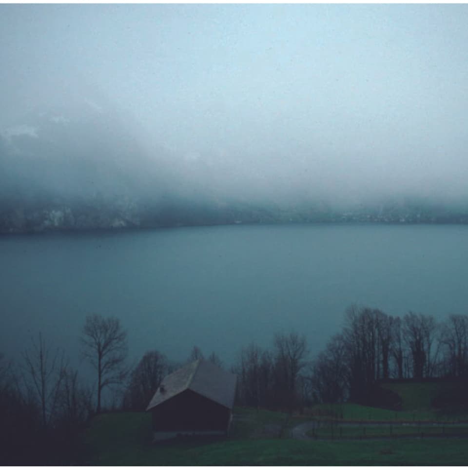 Eine mächtige Regenwolke hängt über einem See, das andere Ufer erkennt man nur noch knapp.