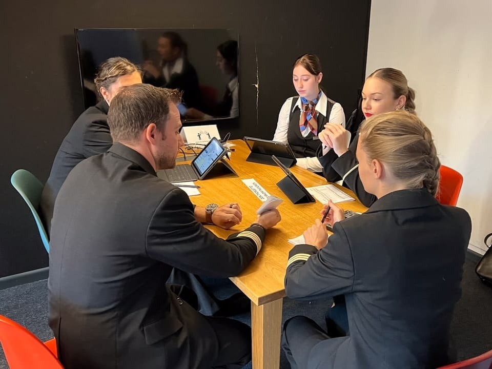 Fünf Menschen in Uniform sitzen an einem Tisch und besprechen etwas. 