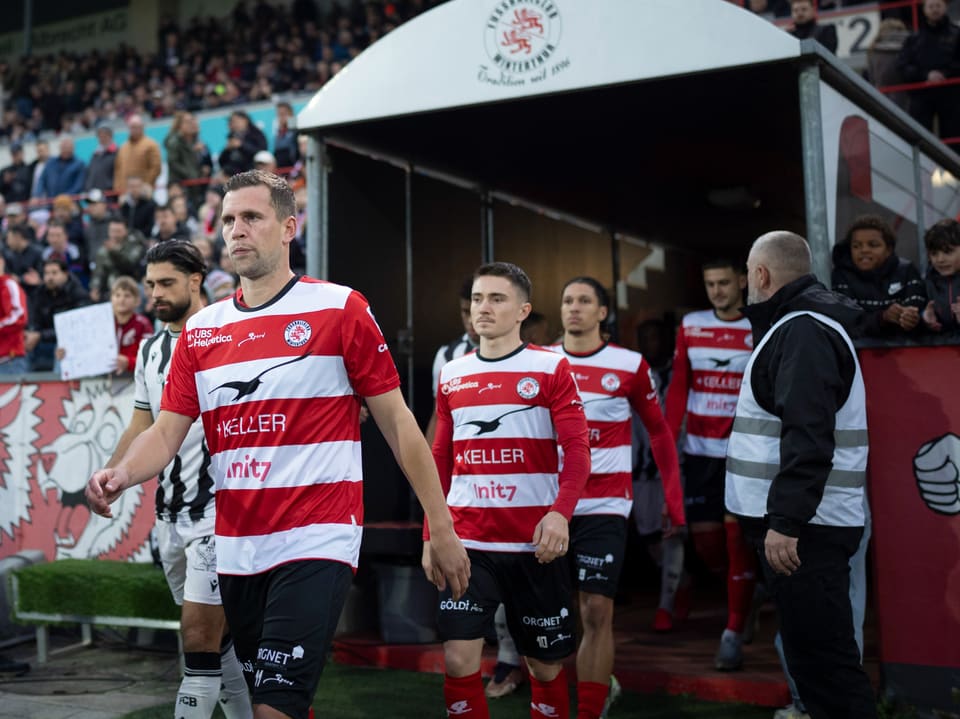 Fussballspieler betreten das Spielfeld aus dem Stadiontunnel.