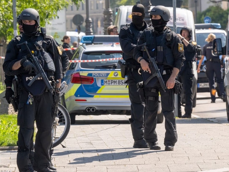 Bewaffnete Polizisten in Schutzkleidung vor einem Polizeiauto.