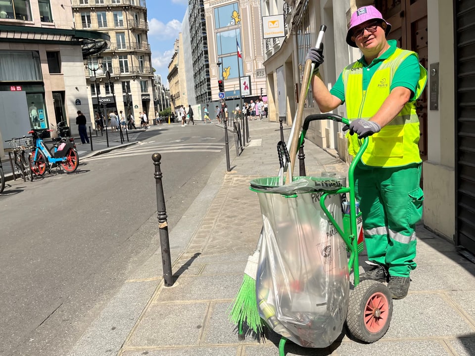 Strassenreiniger Ludovic Franceschet in gelber Weste mit Reinigungswagen in einer Stadtstrasse.