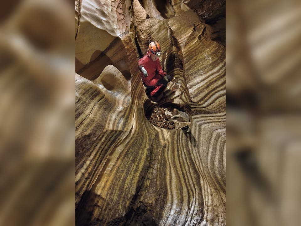 Speläologe in gestreifter Felsenhöhle.