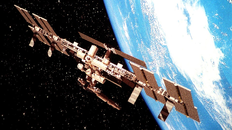 Bild der Internationalen Raumstation ISS vor dem hellen Blau der Erdkugel.