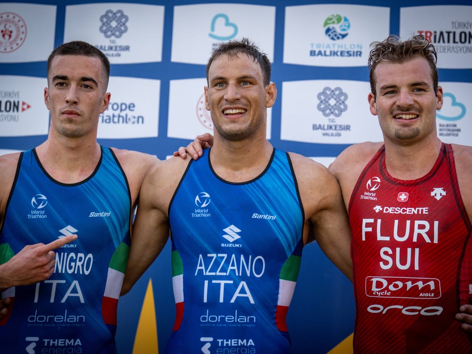 Drei Triathleten in Wettkampfkleidung auf dem Podium beim Triathlon Balıkesir.