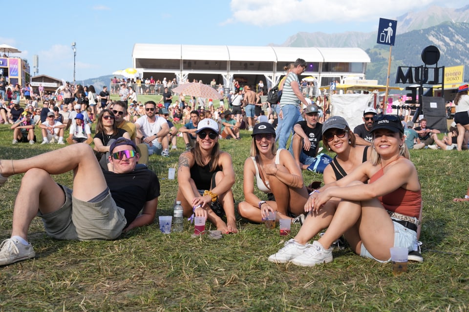 Gruppe von Freunden sitzt auf dem Gras bei einem Festival am Open Air Lumnezia 2024.