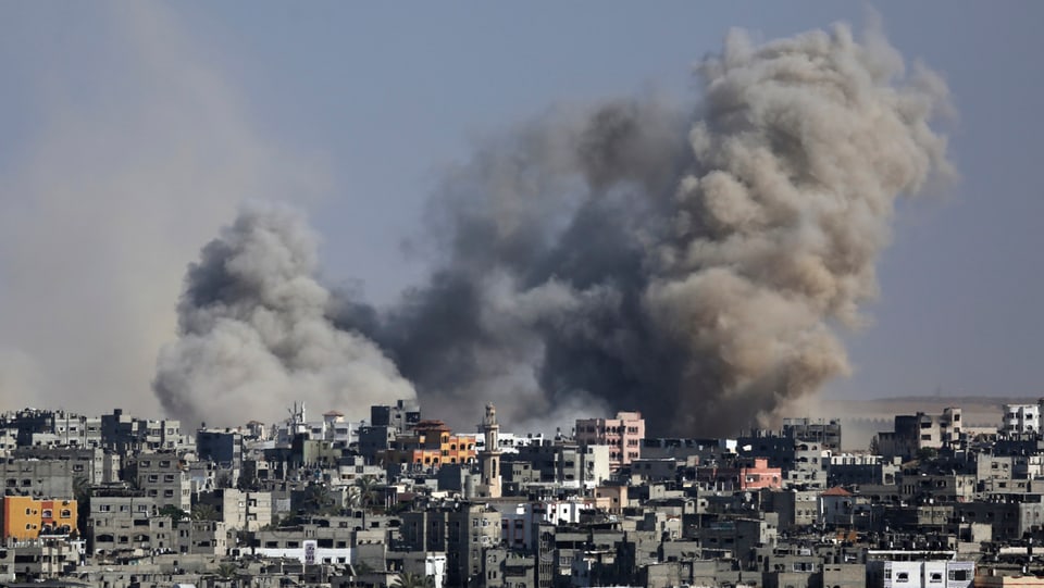 Rauchwolken am Horizont über dem Gazastreifen. Dicht besiedeltes Gebiet im Vorderdrund.