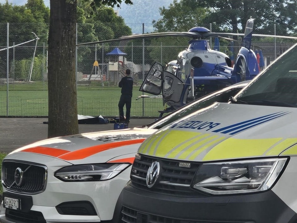 Polizeiautos und ein Rettungshubschrauber neben einem Sportplatz.