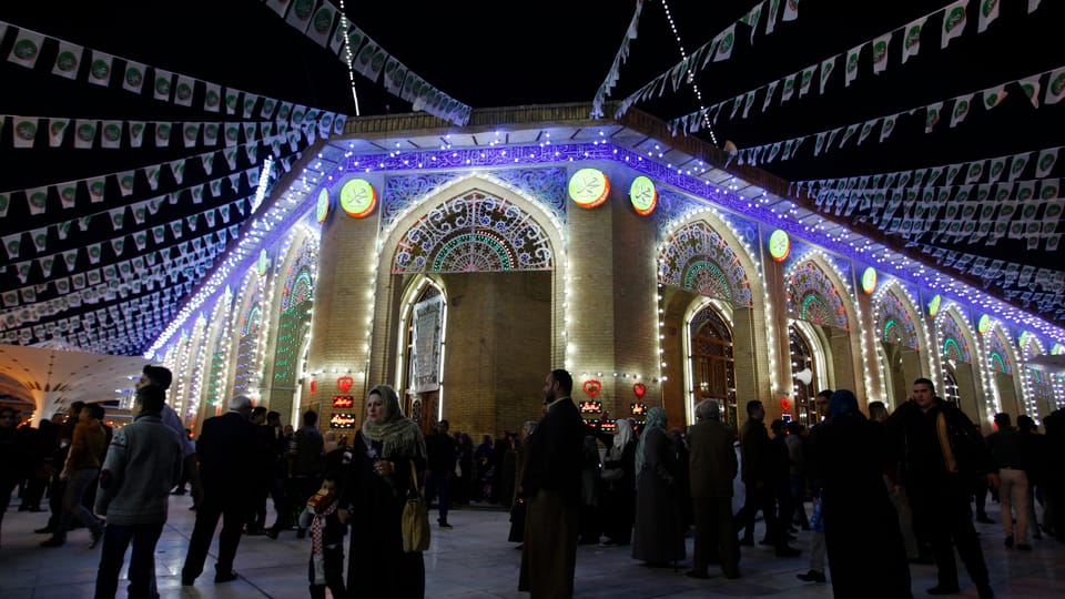 Mit Lichtern dekorierte Moschee in Bagdad, Menschen davor