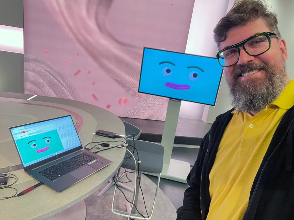 Mann vor Laptop und Monitor mit Cartoon-Gesicht