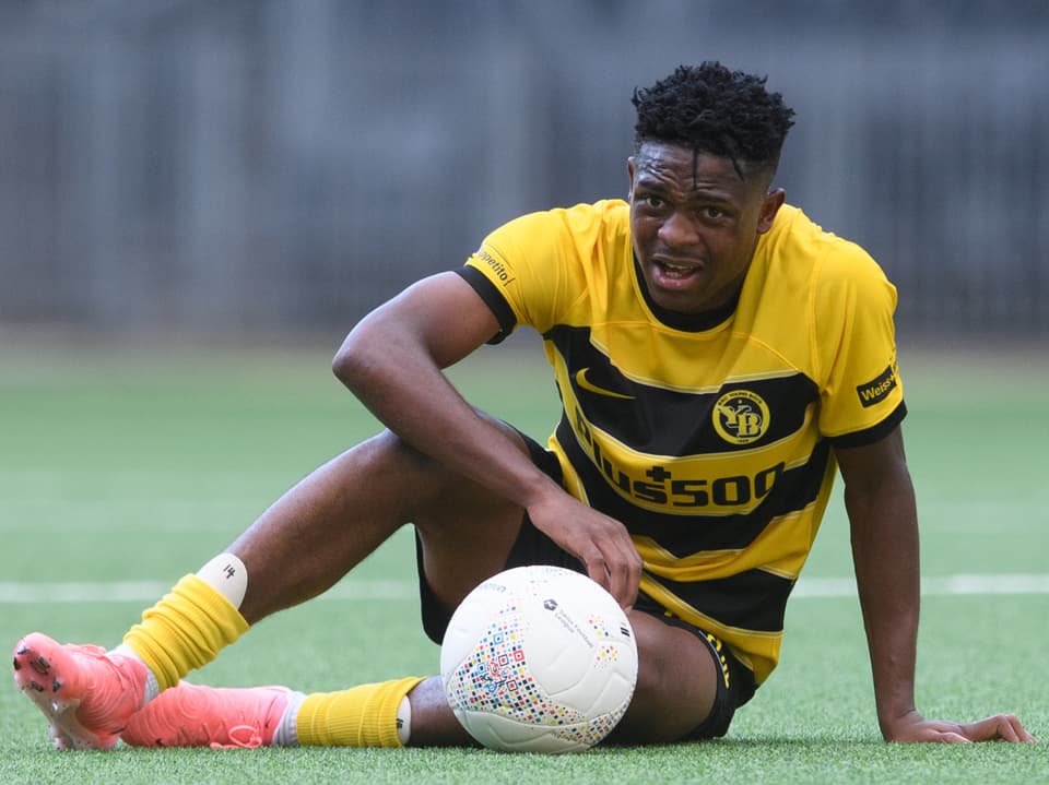 Fussballspieler in gelb-schwarzem Trikot auf dem Spielfeld sitzend.