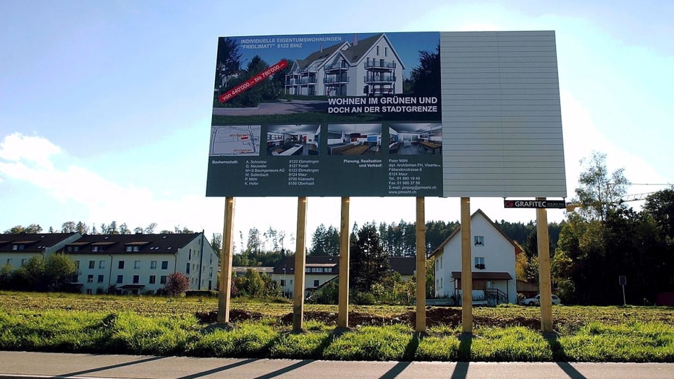 Werbetafel mit Wohnungsbau-Projekt auf grüner Wiese.