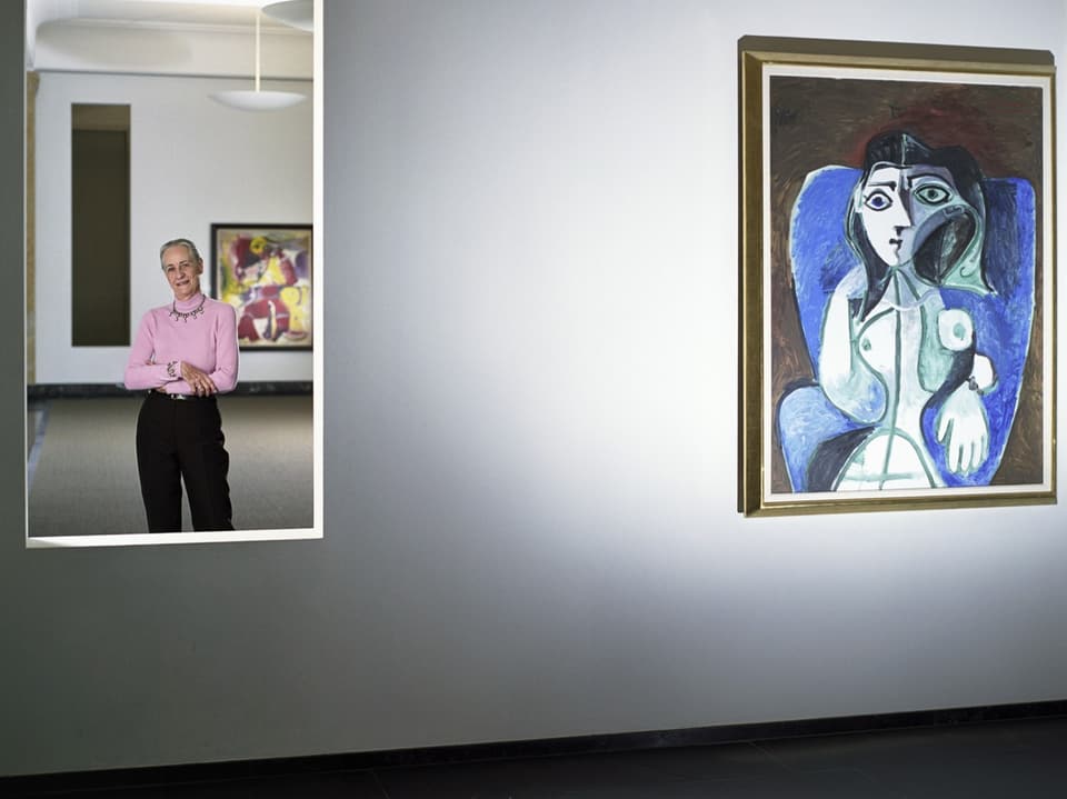 Angela Rosengart schaut durch eine Aussparung in der Wand. Daneben ein Bild von Picasso.