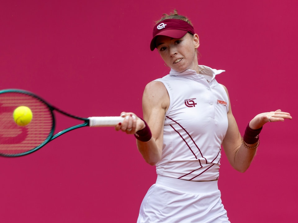 Tennisspielerin schlägt Ball vor pinkem Hintergrund.