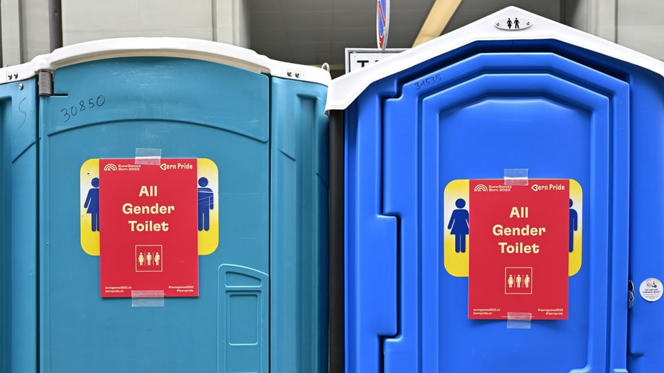 Auf zwei Toi-Toi-Toiletten sind die Geschlechtssymbole überklebt mit einem Schild. Darauf steht «All Gender Toilet». 