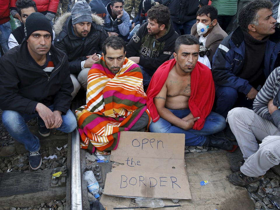 Ein Iraner hat sich an der griechisch-mazedonischen Grenze den Mund zugenäht. Weiter Männer sitzen in einem stillen Protest um ihn herum. (reuters)