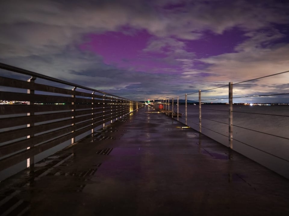 Nachtblick auf einen beleuchteten Pier mit Wolkenhimmel.