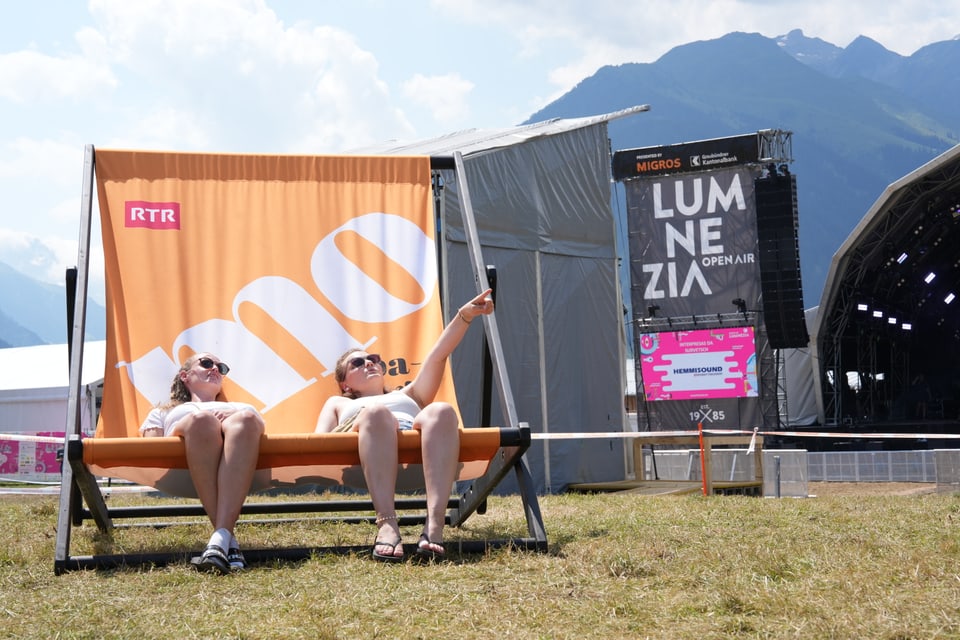 Zwei Personen entspannen auf einem Liegestuhl beim Lumnezia Open Air Festival am Open Air Lumnezia 2024.