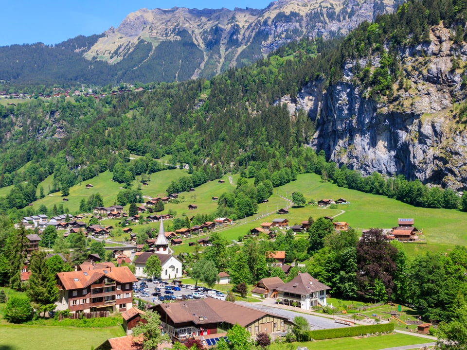 Schweizer Bergdorf mit grünen Wiesen und Kirche im Tal.