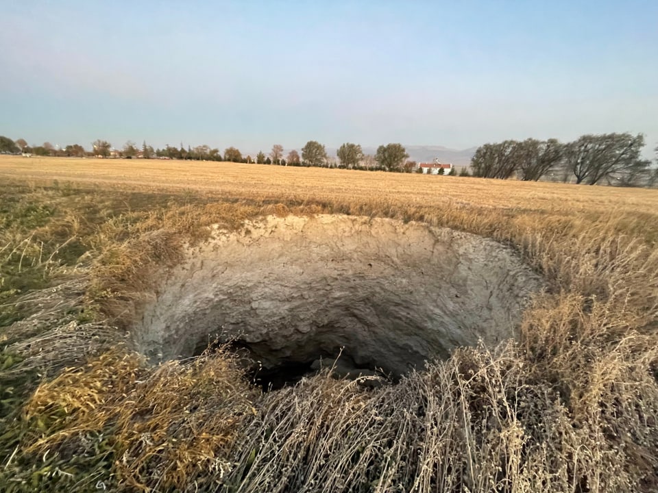 Mitten im Feld klafft ein metertiefes Loch