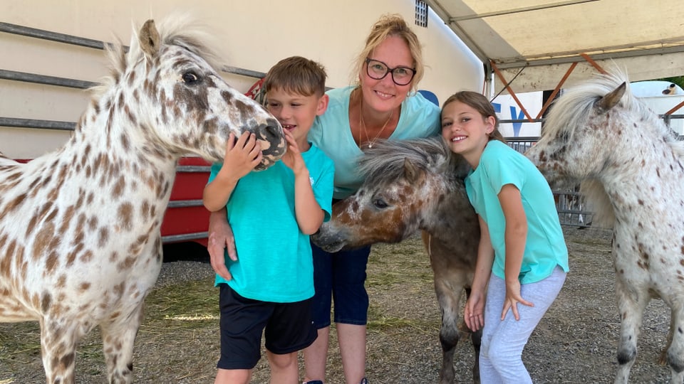 Mia Stey und ihren Kindern Simone (10) und Rolf (7) lächeln mit drei mittelgrossen Ponys in die Kamera.