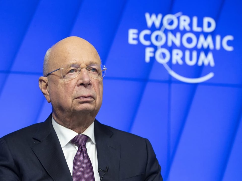 Ein Mann in Anzug und Krawatte vor einem blauen Hintergrund. Darauf steht "World Economic Forum"
