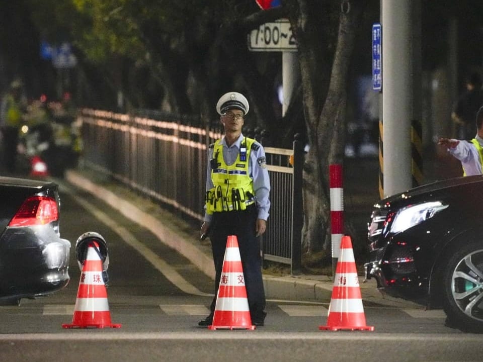 Polizist steht nachts zwischen Verkehrshütchen auf Strasse.