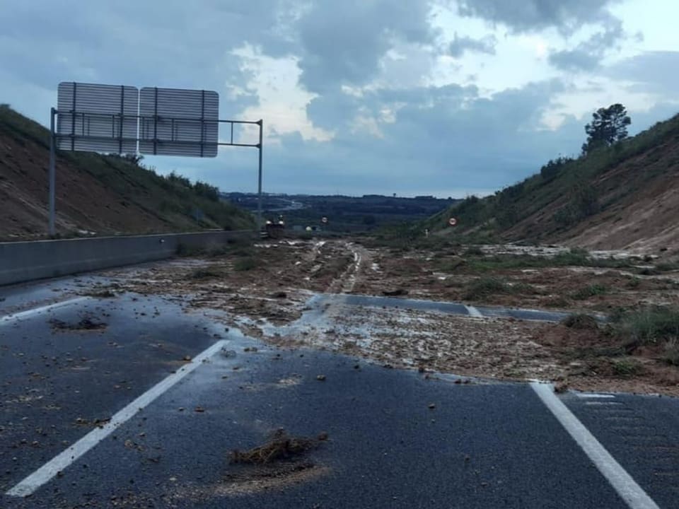 Verschlammte Autobahn nach Erdrutsch zwischen Hängen.