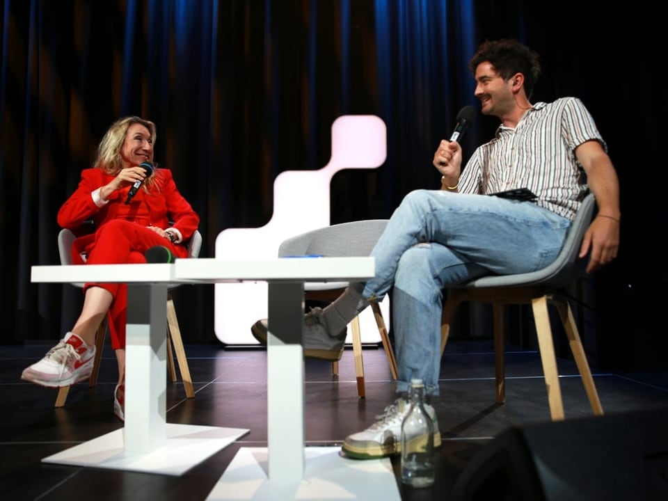 Komikerin Tamara Cantieni und Moderator Dario Cantieni sitzen auf der Bühne am «SRF 3 Comedy-Zmorge» im Mai.