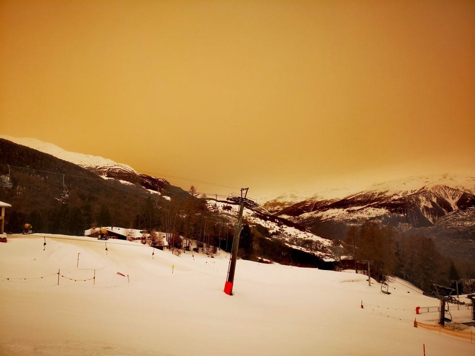 Oranger Himmel und weisse Schneelandschaft.