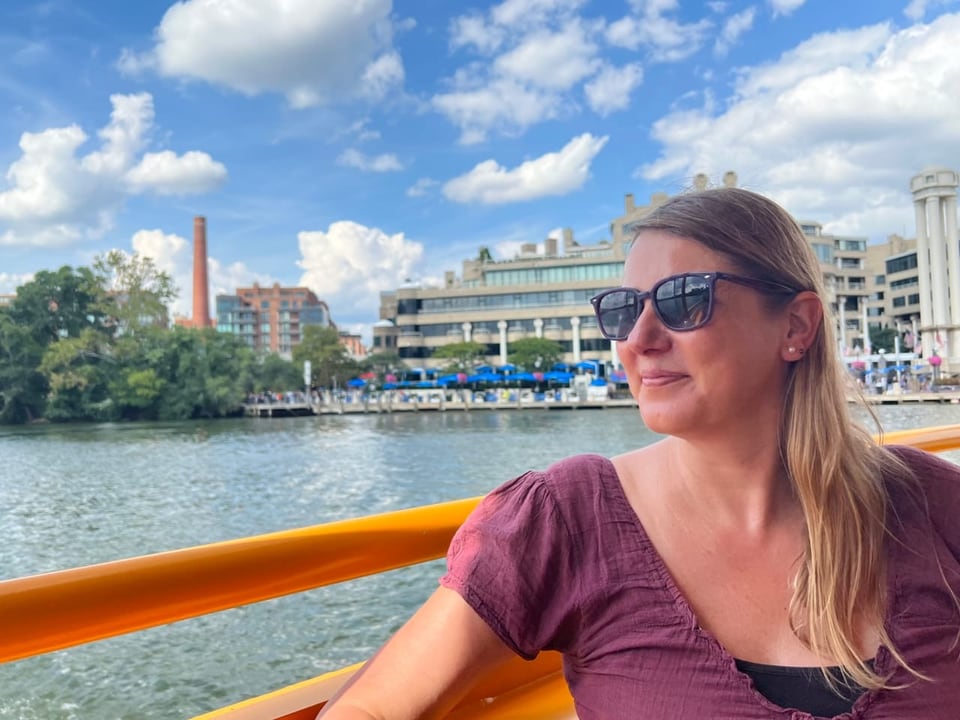 USA-Korrespondentin Barbara Colpi sitzt mit einer Sonnenbrille am Potomac River in Washington.