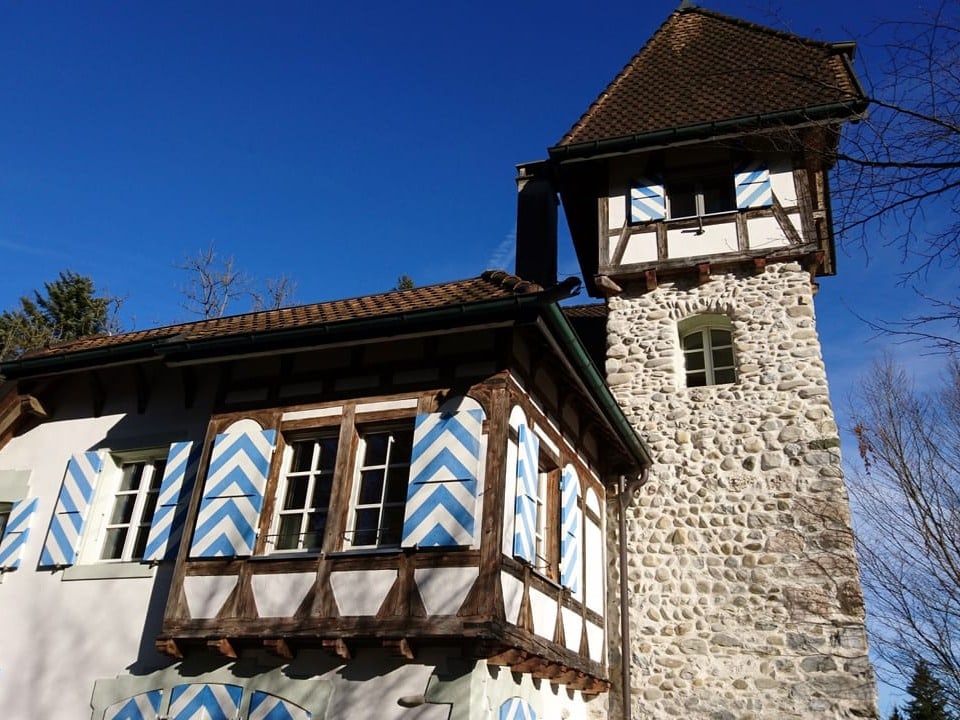 Eine Burg mit blau-weissen Jalousien und einem Türmchen.