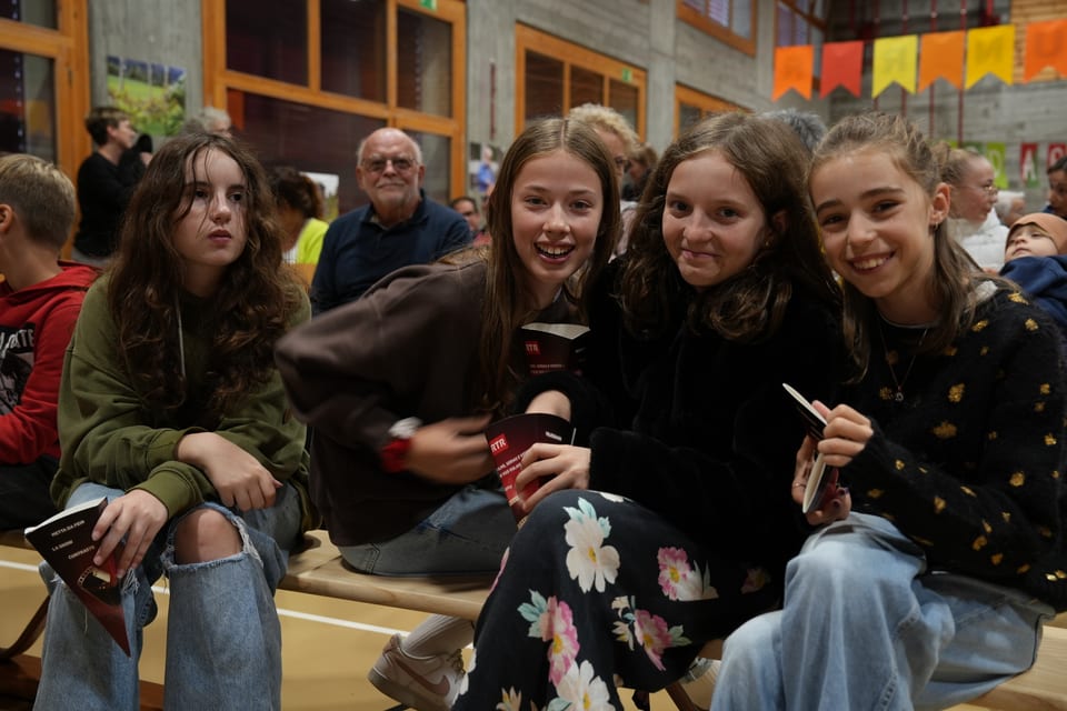 Vier Mädchen sitzen mit Broschüren in einer Halle.