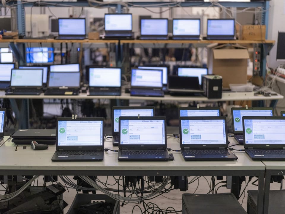 Mehrere Laptops auf Tischen in einem Laborraum.