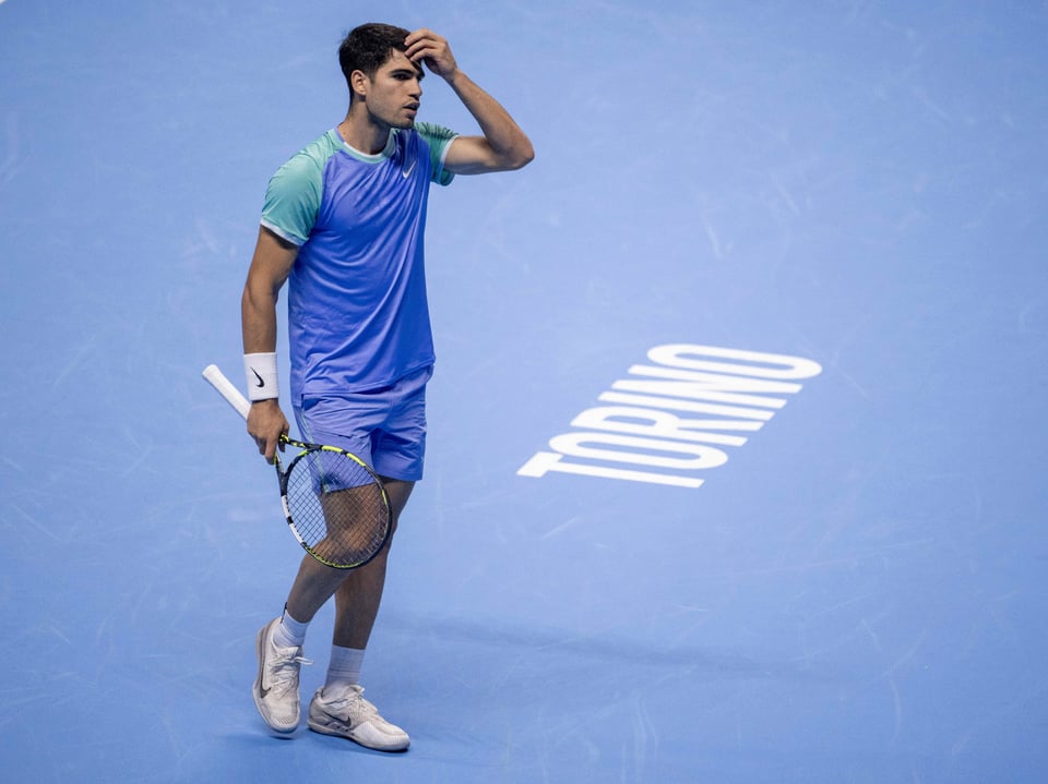 Tennisspieler auf blauem Platz, hält Schläger und berührt Kopf.