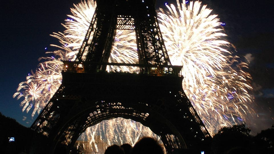 Feuerwerk hinter dem Eiffelturm bei Nacht.
