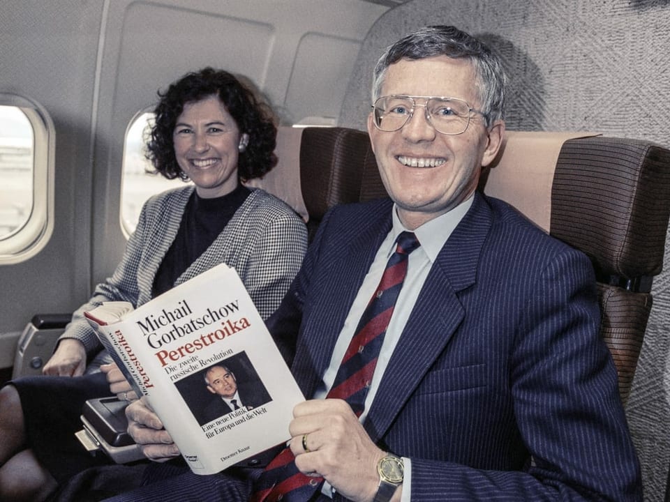 Kaspar Villiger mit Buch «Perestroika» auf einem Flugzeugsitz. Neben ihm sitzt Ehefrau Vera.