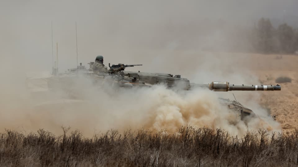 Panzer fährt durch staubige Landschaft.