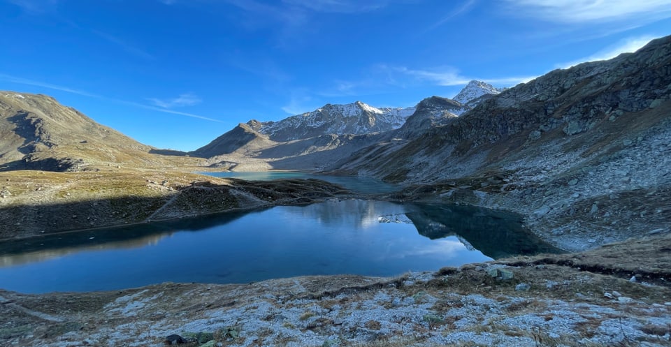 Bergsee in alpiner Landschaft mit schneebedeckten Gipfeln.