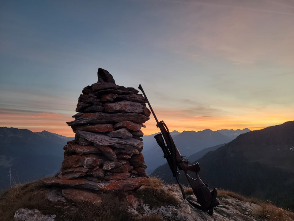 Steinhaufen mit Gewehr im Sonnenuntergang.