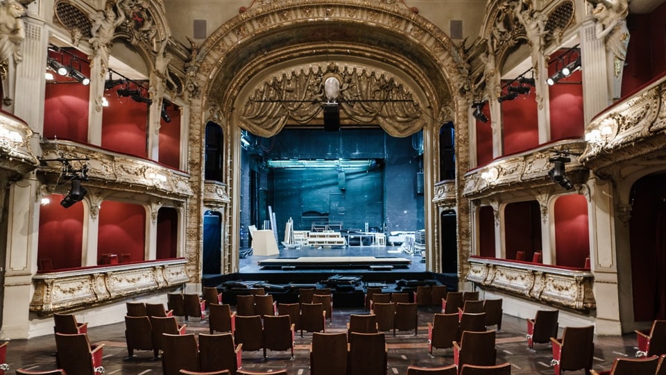 Historisches Theater mit eleganten roten Sitzreihen und verzierten Balkonen.