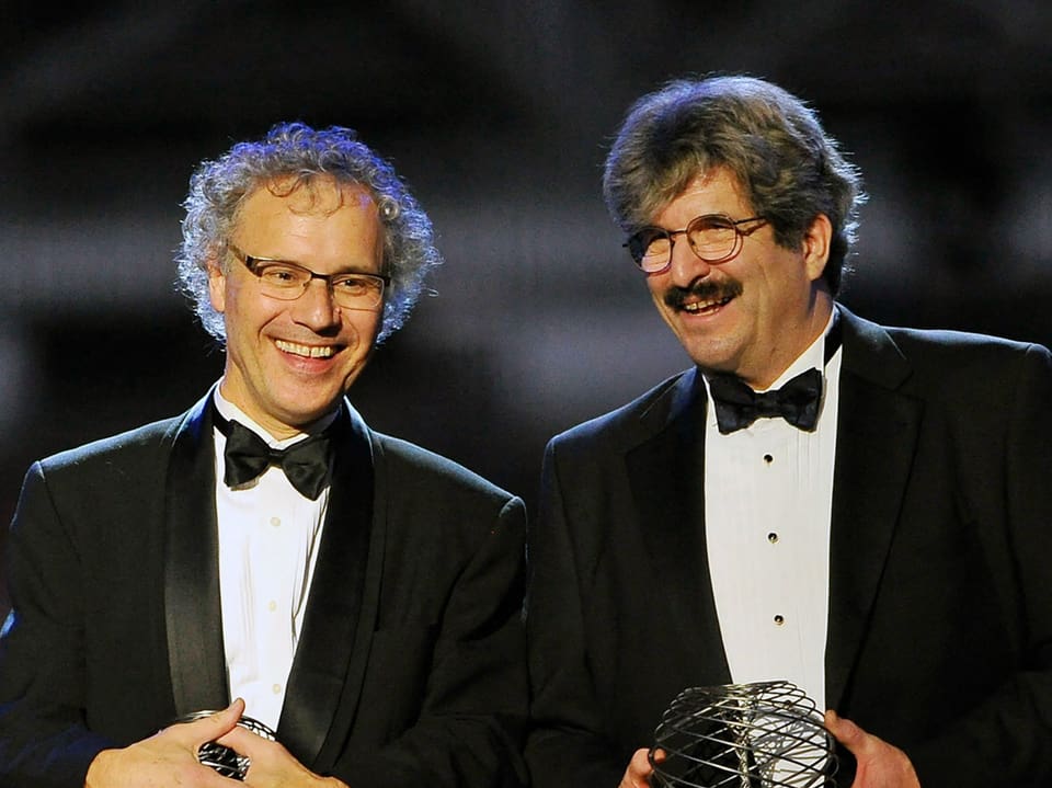 Zwei Männer in Smoking mit Trophäen.