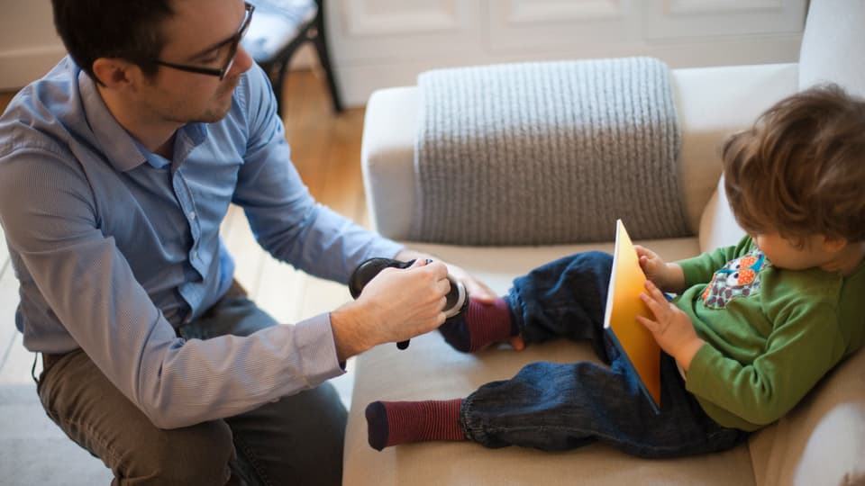 Vater zieht seinem Sohn die Schuhe an