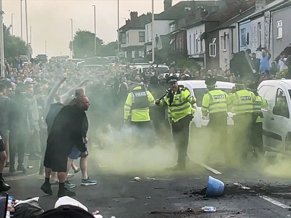 Strassenprotest mit Polizei und Menschenmenge in Rauch.